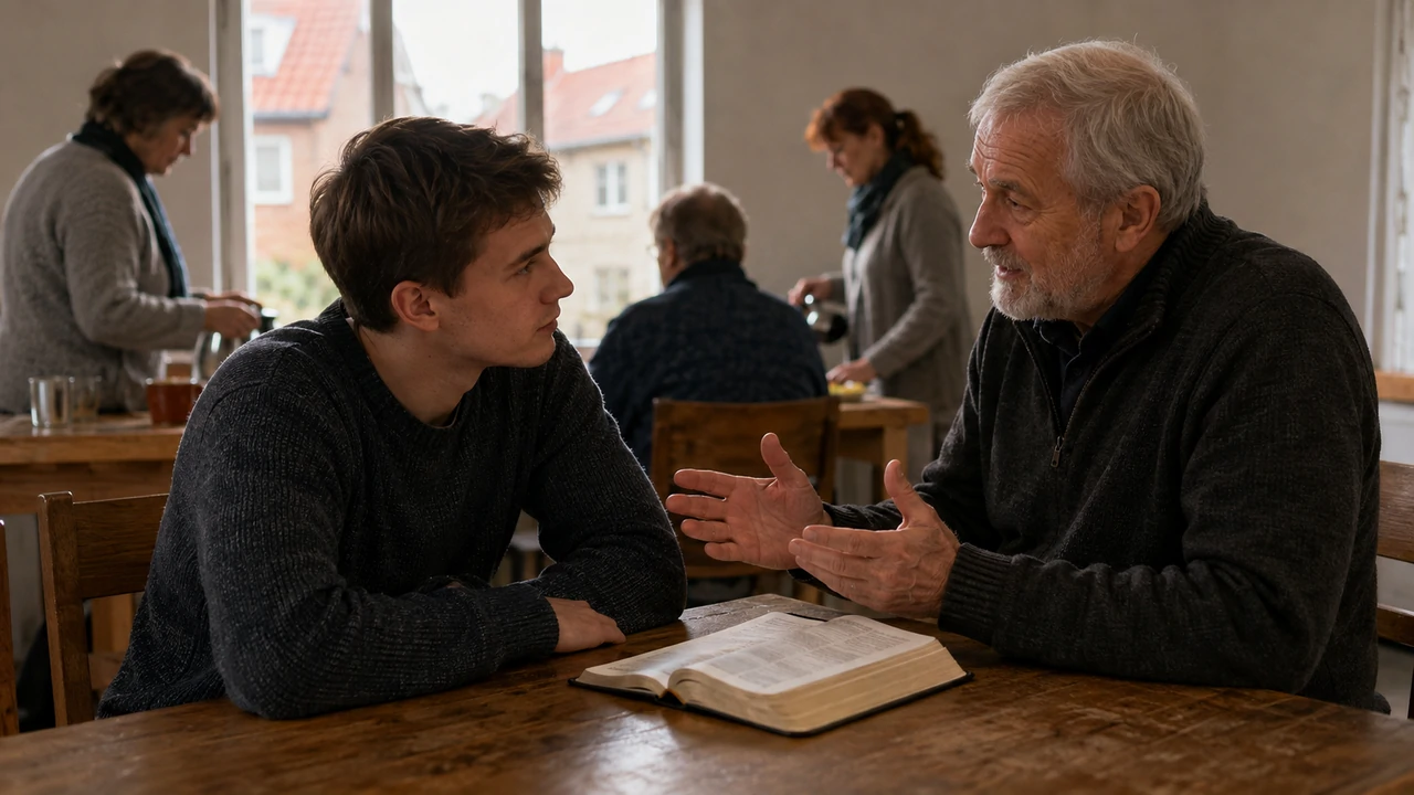 A young man listens to an older Christian mentor beside an open Bible in a modest community room while others prepare refreshments behind them.
